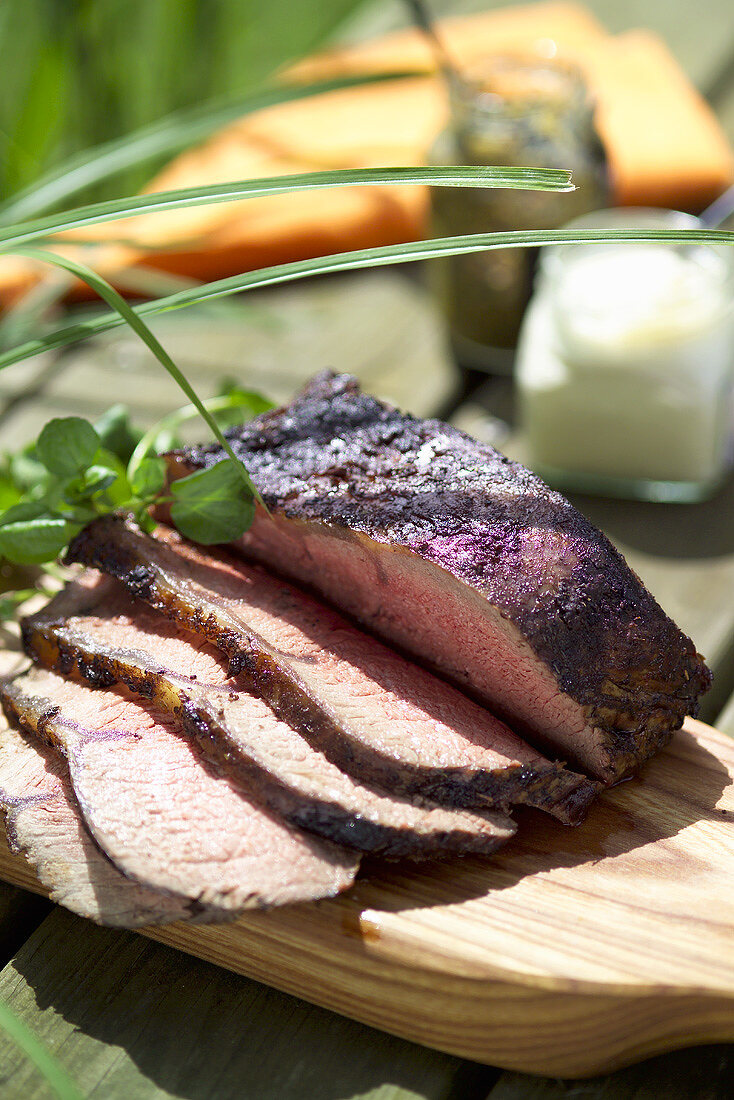 Roastbeef in Scheiben auf einem Holztisch im Freien