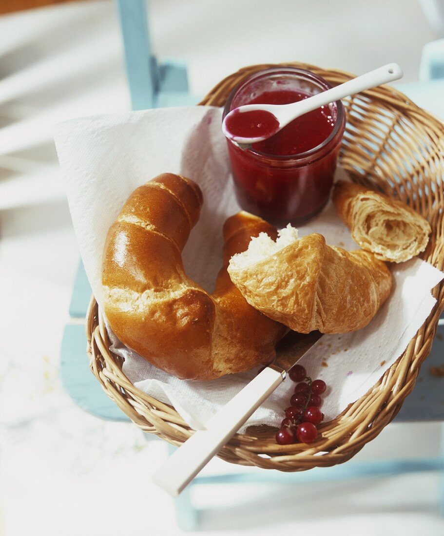 A jar of redcurrant and vanilla jam with croissants