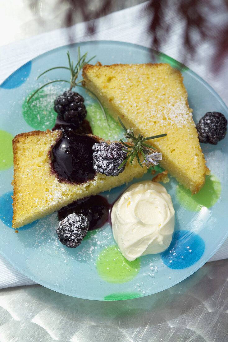 Zitronenkuchenstücke mit Brombeeren und Schlagsahne