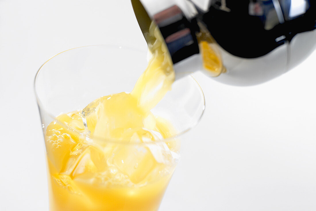 Frucht-Cocktail aus einem Shaker in ein Glas gießen