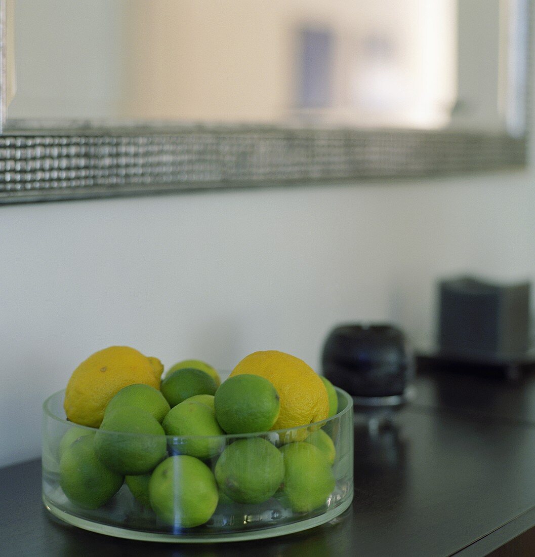 Limes and lemons in a glass bowl on a cabinet