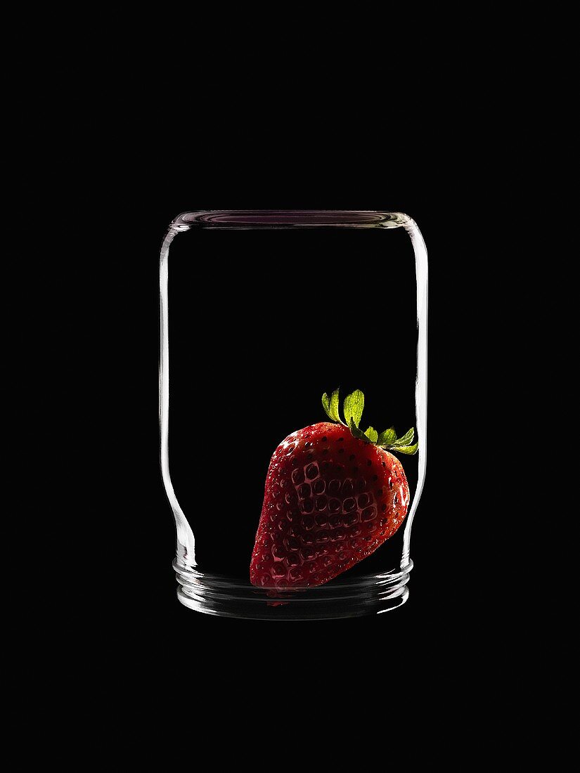 A strawberry in an upturned yoghurt jar