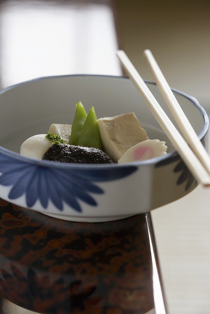 Steamed vegetables and tofu in a bowl with chopsticks