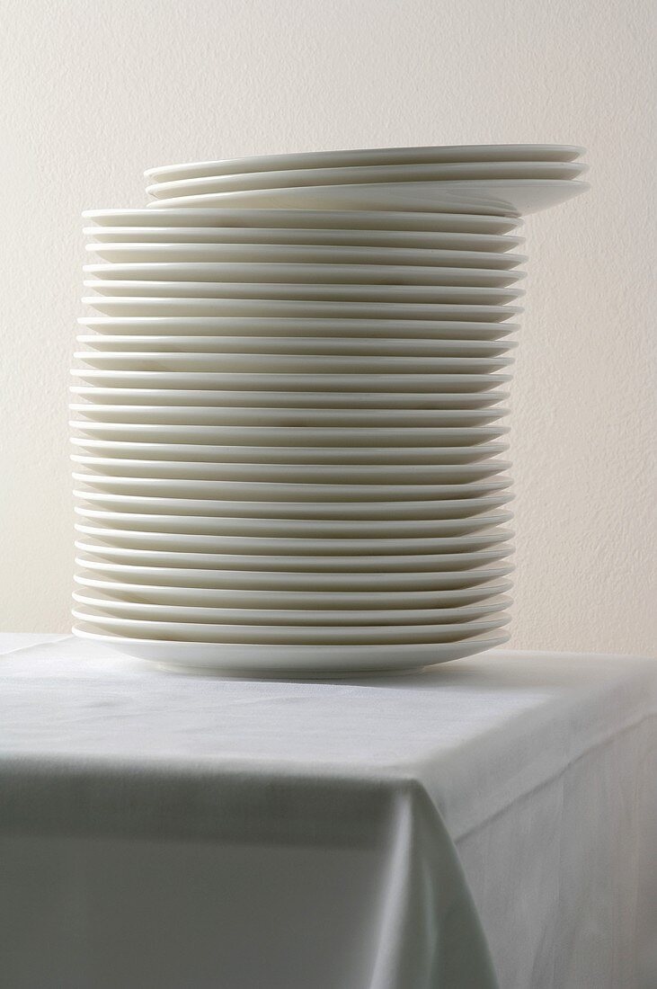 A stack of porcelain plates on a table with a tablecloth