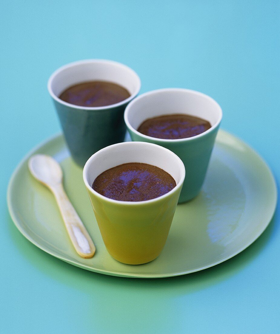 Three beakers of chocolate mousse on a plate