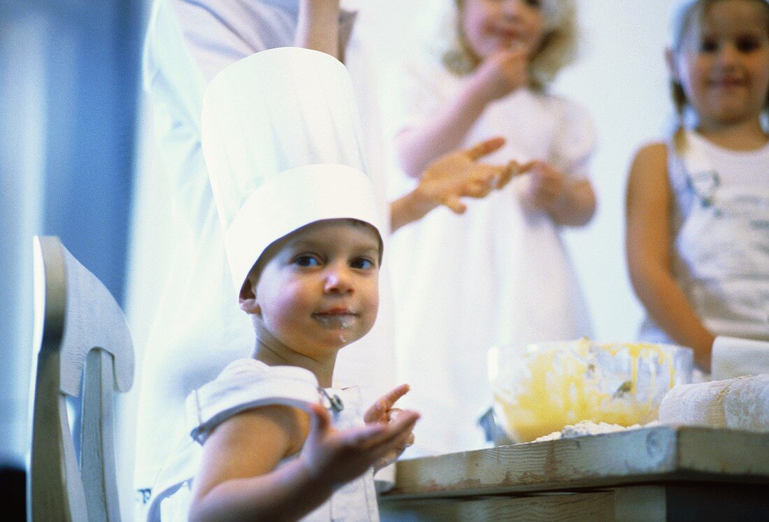 Little boy baking, siblings watching