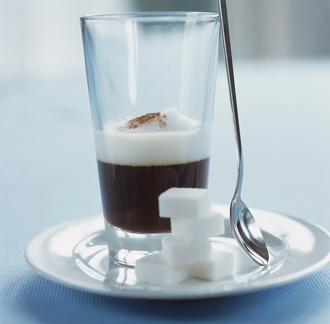 Ein Glas Espresso Macchiato und Zucker