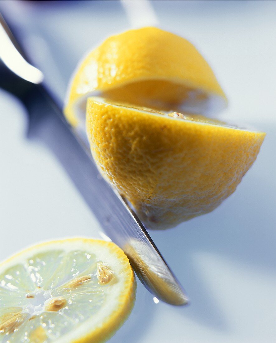 Zwei Zitronenhälften und eine Zitronenscheibe mit Messer