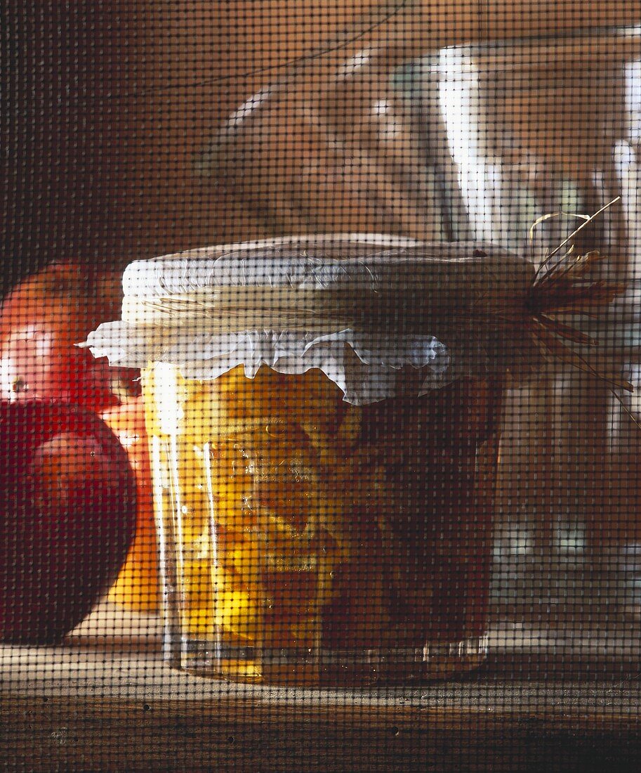 Caramelised apple preserve in a glass jar behind a fly screen