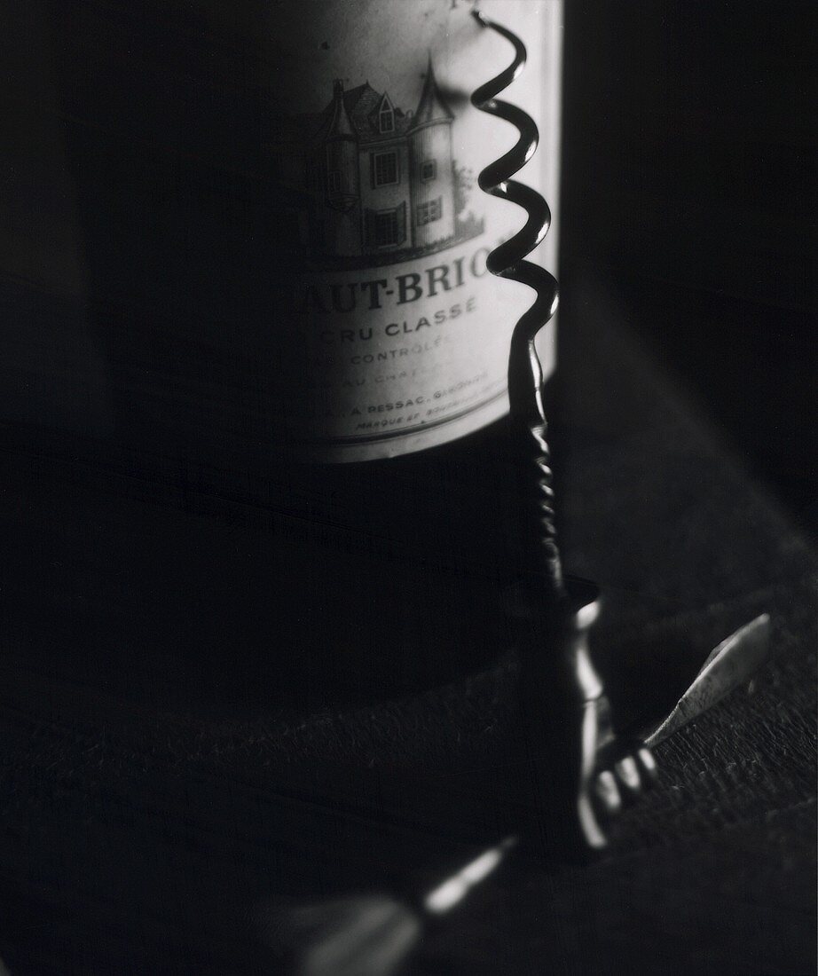 Bottle of 1967 Chateau Haut-Brion, corkscrew in front (b/w)