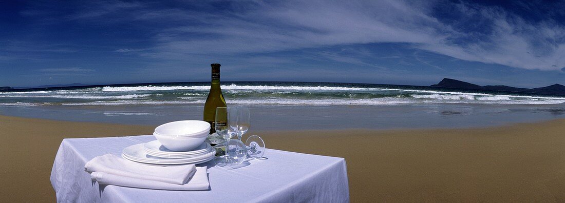 Table with White Wine and Dinnerware at the Beach