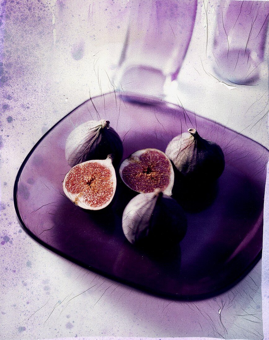Whole and opened figs on glass plate