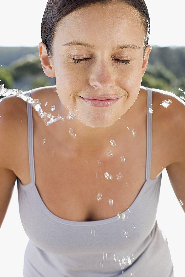A young woman splashing water on her face