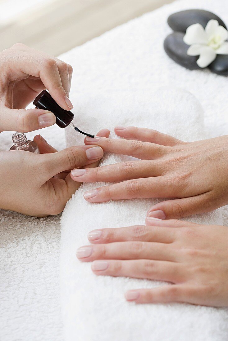 A woman having nail polish applied as part of a manicure