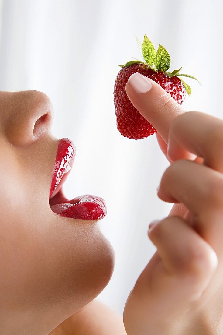 A woman holding a strawberry