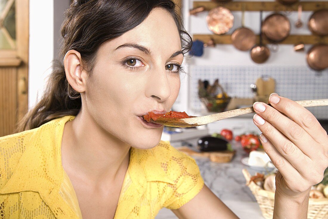 An Italian woman tasting sauce