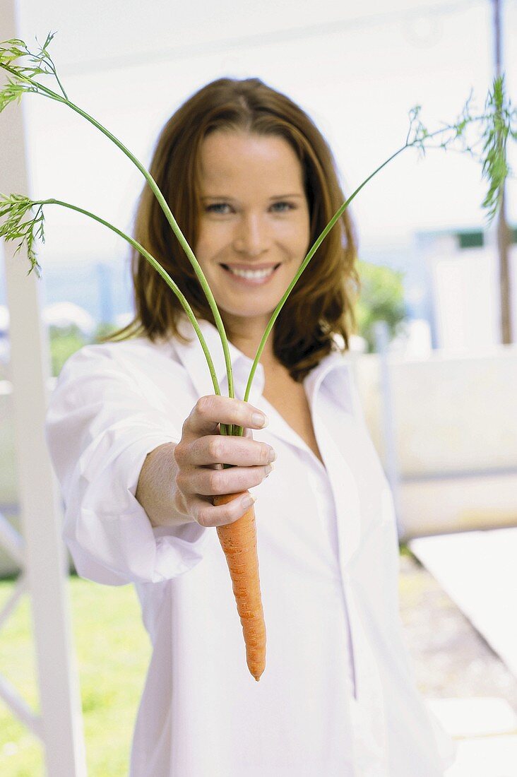 A young woman holding a carrot