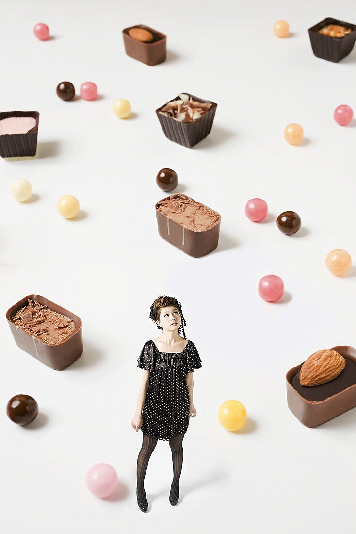 A small woman surrounded by large sweets