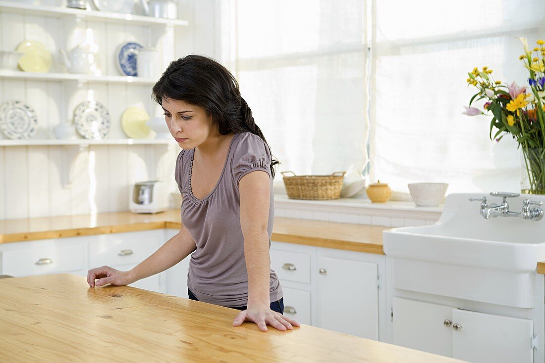 Traurig aussehende Frau steht in der Küche