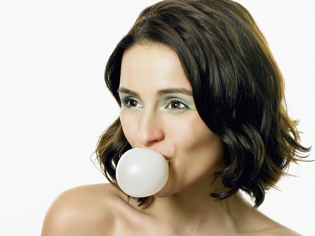 A young woman blowing a bubble with chewing gum