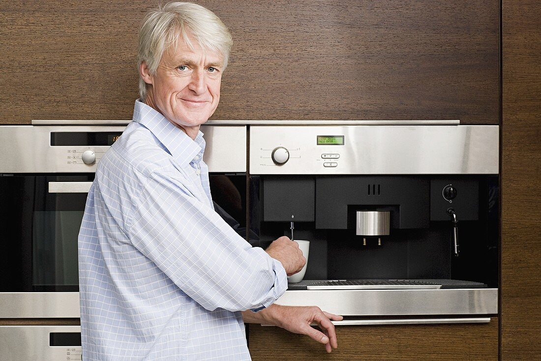 A middle aged man waiting for coffee from coffee machine
