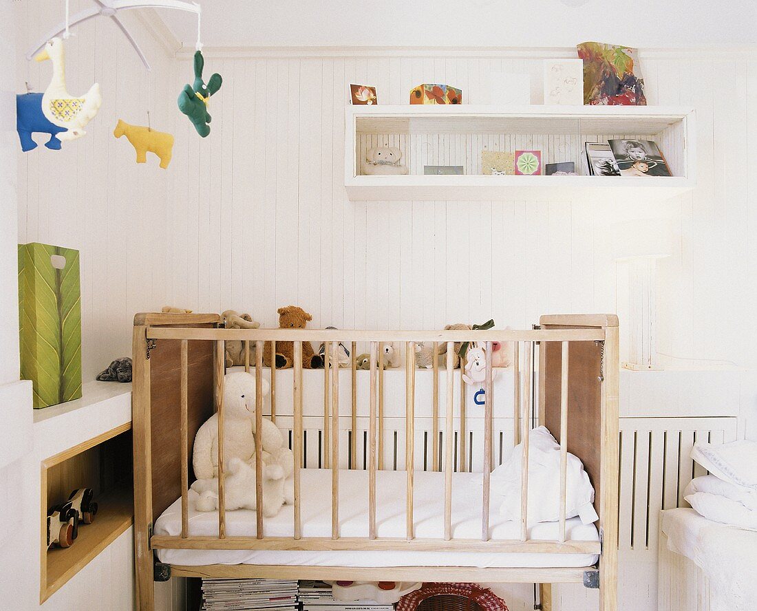 Baby-Schlafzimmer mit Teddybären im Kinderbett und einem lustigen Tiermobile