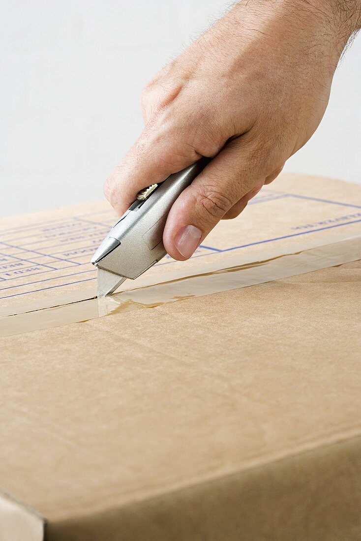 A man opening a box with a carpet knife