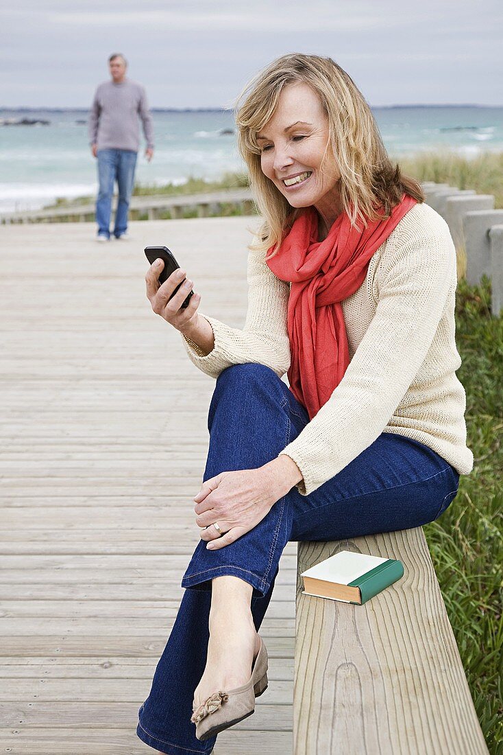 Frau an der Küste mit Smartphone