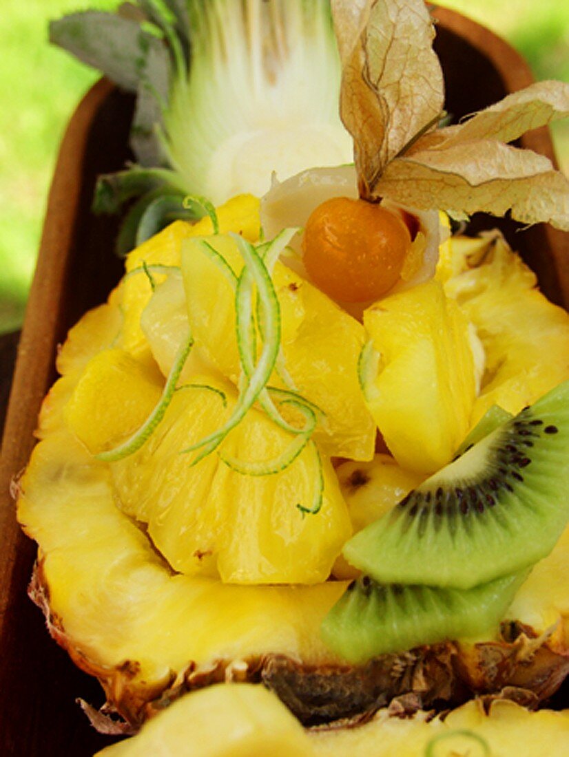 Exotischer Fruchtsalat mit Ananas und Physalis in Holzschale
