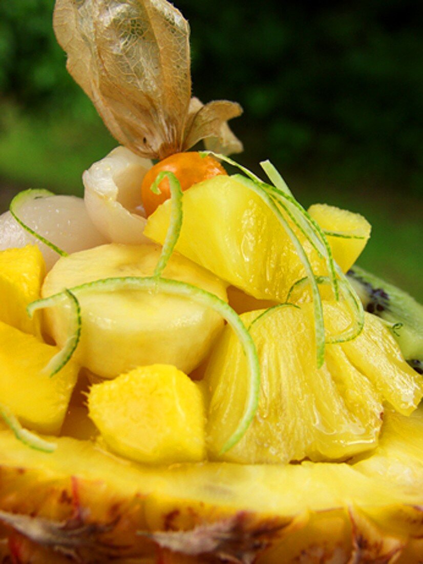 Exotischer Fruchtsalat mit Limettenzesten in Ananashälfte