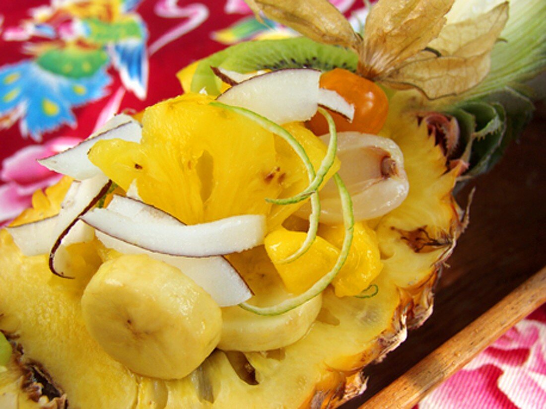 Exotic fruit salad with coconut shavings in half a pineapple