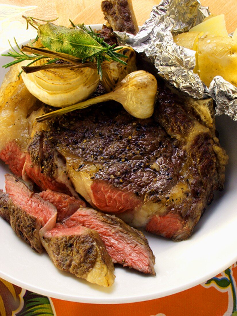 Barbecued ribeye steak with garlic and baked potato