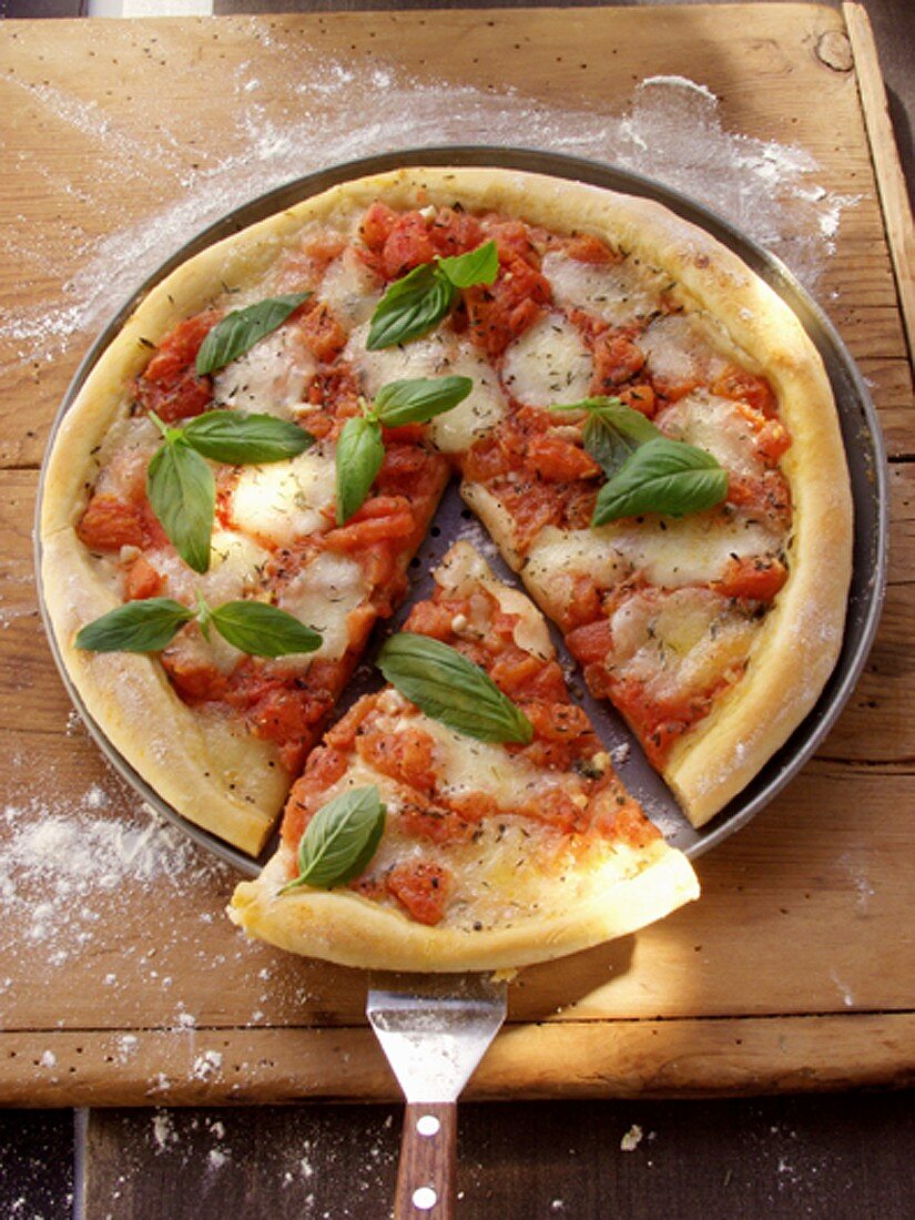 Pizza mit Tomaten, Käse und Basilikum (angeschnitten)