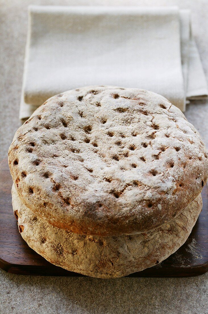 Rustikale Fladenbrote auf Holzschneidebrett vor Leinentuch