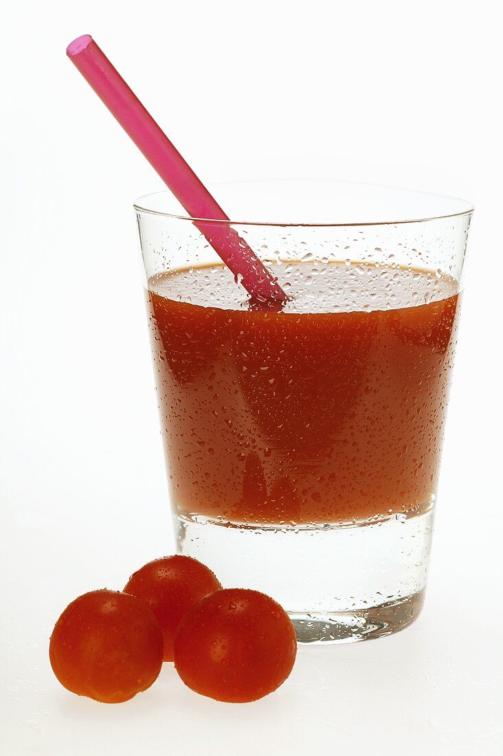 Tomato juice in glass with straw; fresh cherry tomatoes