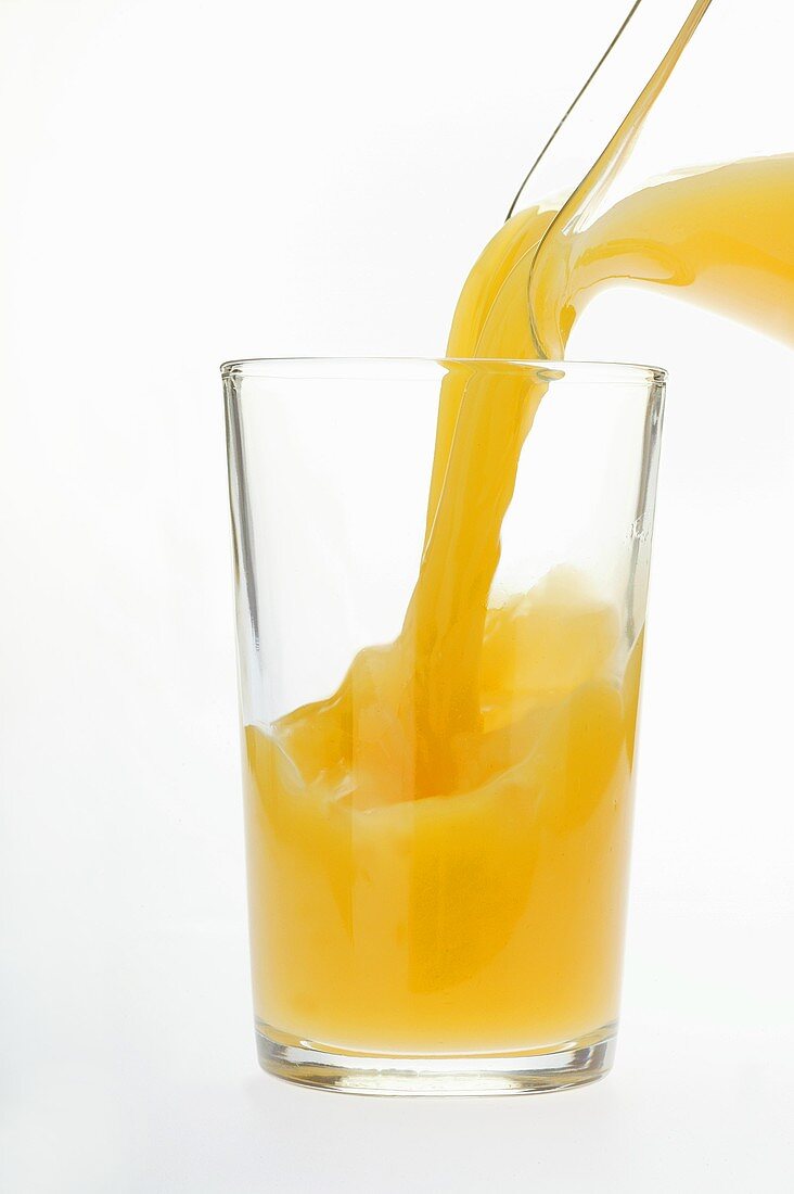 Orangensaft in Saftglas einschenken