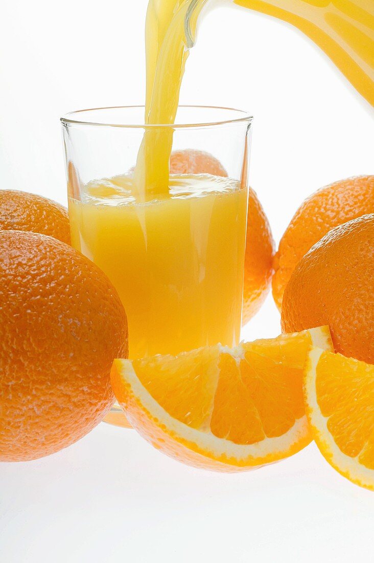 Pouring orange juice; oranges and orange wedges