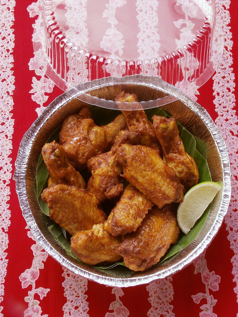 Chicken wings with wedge of lime in aluminium dish