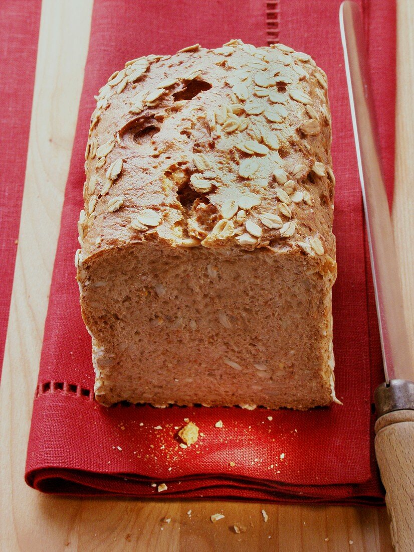 Vollkornbrot mit Haferflocken auf roter Serviette; Messer