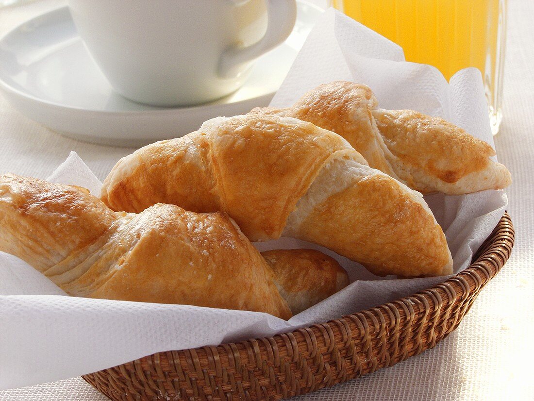 Croissants im Brotkorb, Grapefruitsaft und Kaffeetasse