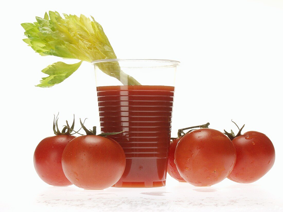 Tomato juice in plastic tumbler with celery; tomatoes