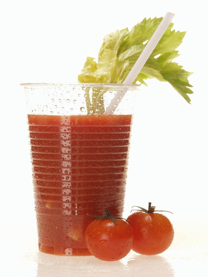 Tomatensaft im Plastikbecher mit Staudensellerie; Tomaten