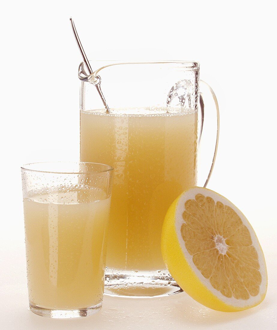 Grapefruit juice in glass and jug beside half grapefruit