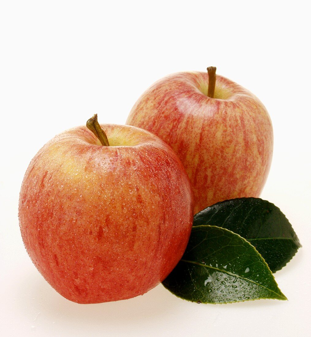 Two red apples with leaves and drops of water