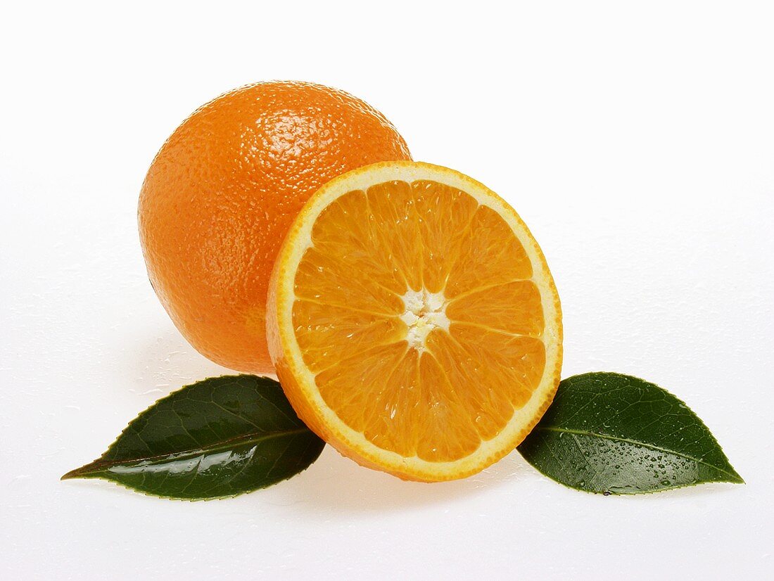 Ganze und halbe Orange mit Blättern und Wassertropfen