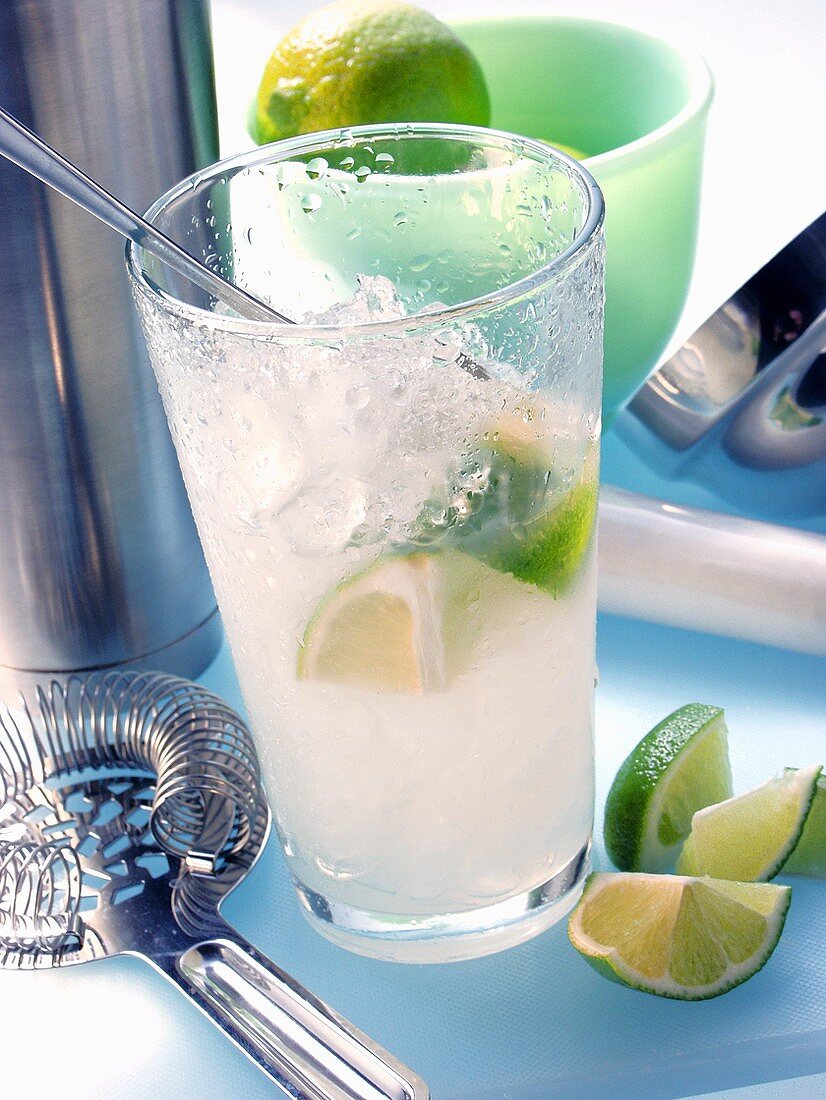 Caipirinha with ice and lime; utensils for mixing drinks