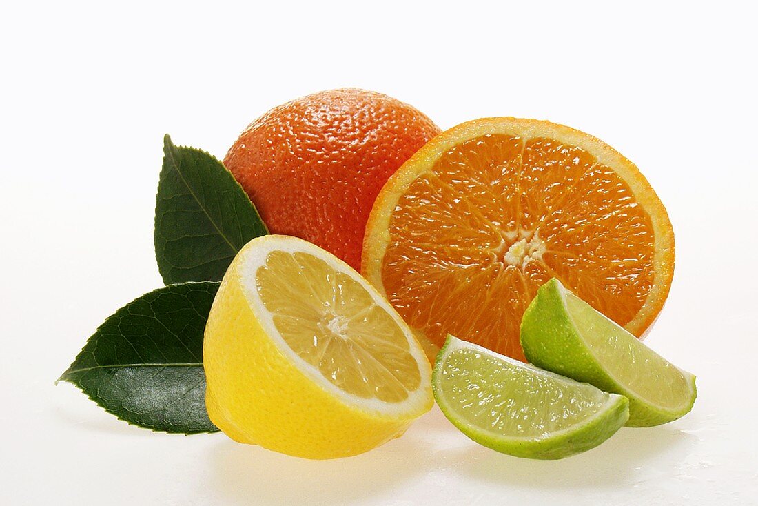 Half a lemon with leaves, oranges and wedges of lime