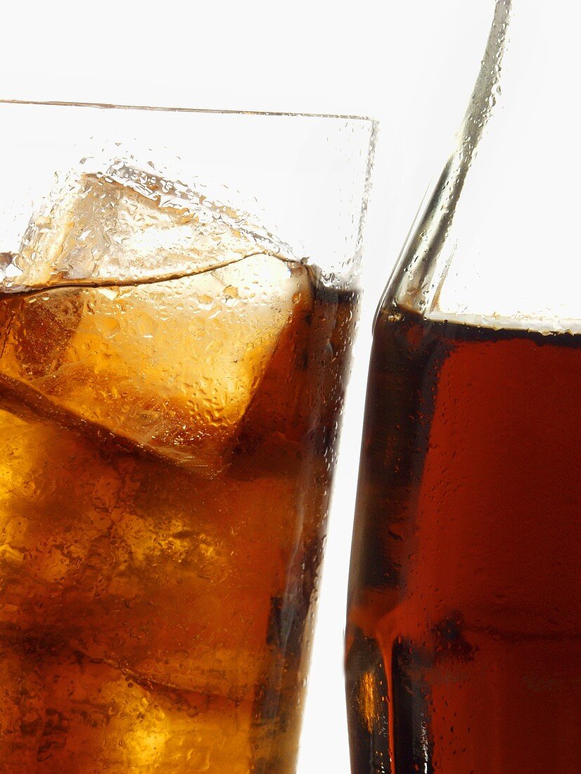 Cola in bottle and glass with ice cubes (close-up)