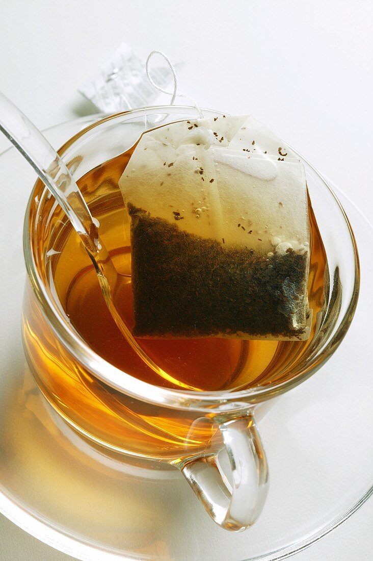Tee in Glastasse mit Teebeutel und Löffel