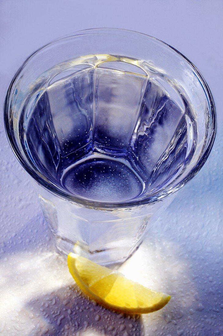 Glass of mineral water in blue; wedge of lemon